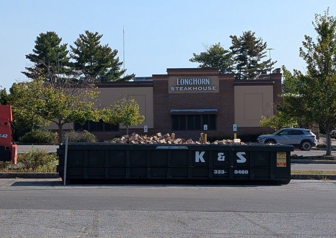 A large green dumpster is parked in front of a store called a center
