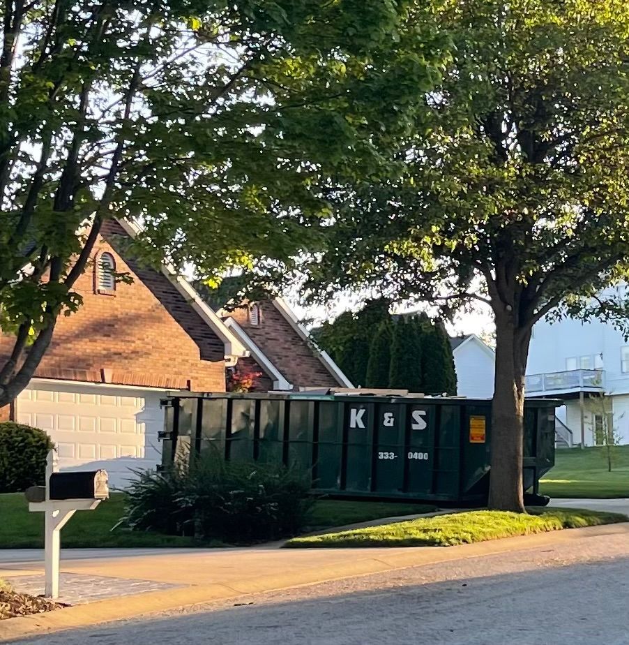 A large green dumpster is parked in front of a store called a center