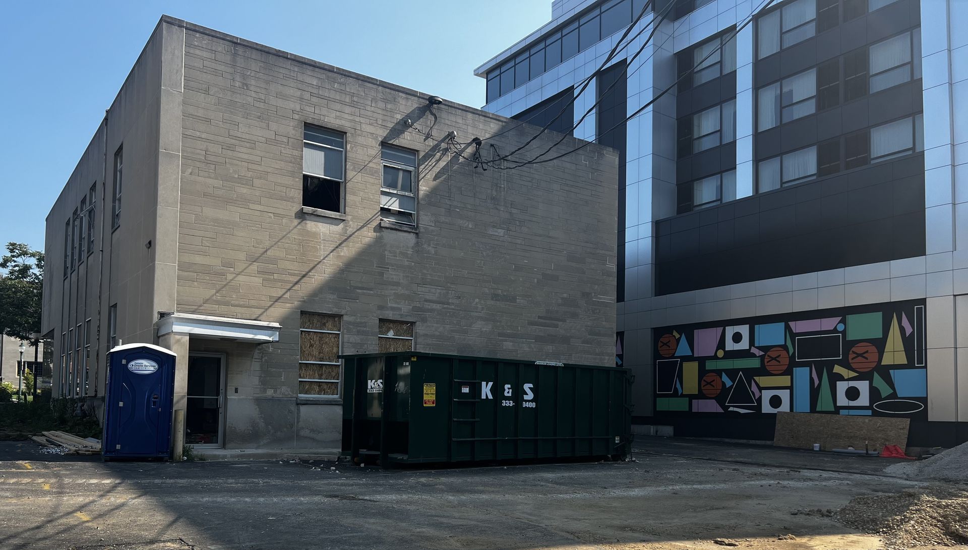 Row of covered garbage bins along a brick wall. Row of covered garbage bins along a brick wall.