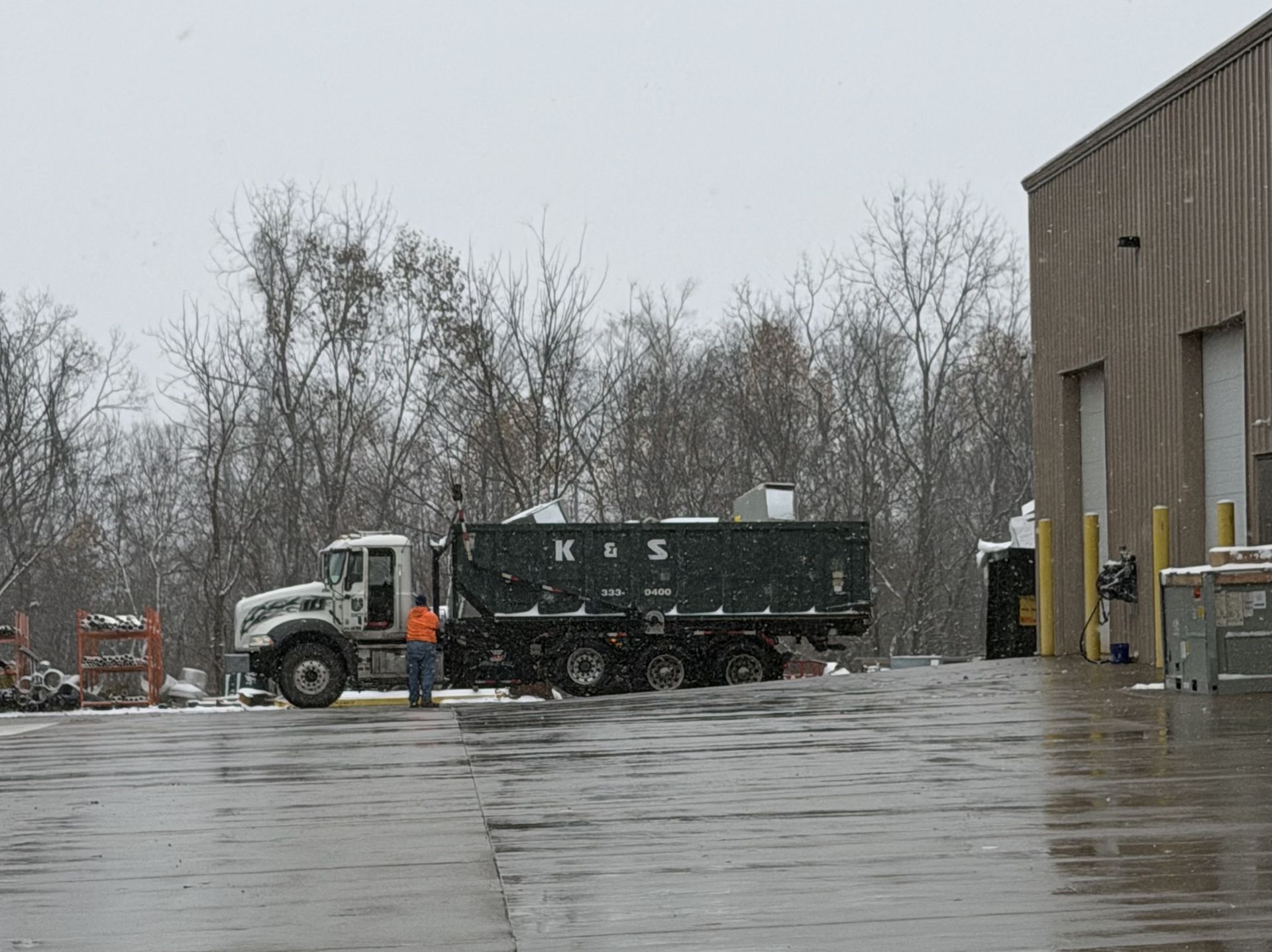 A large green dumpster is parked in front of a store called a center