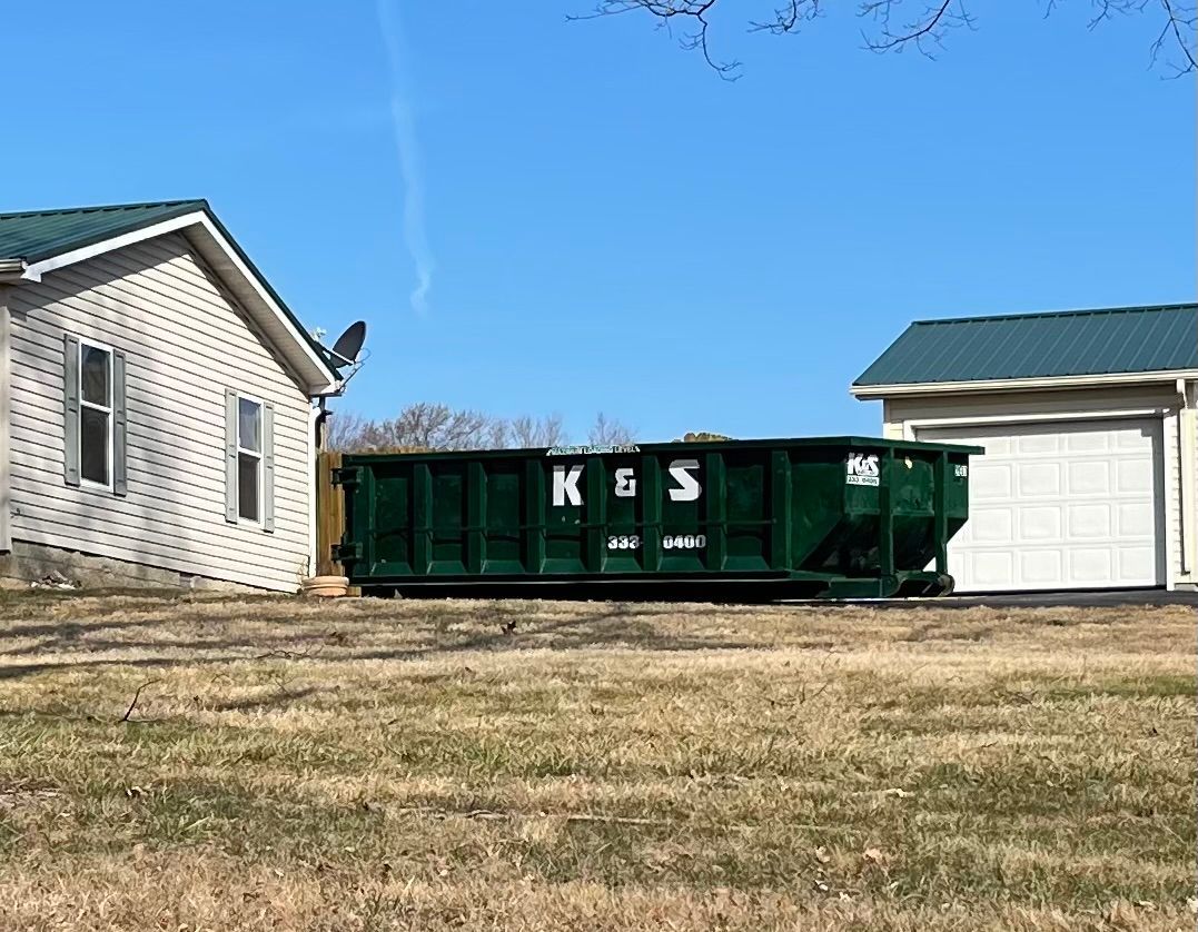 A large green dumpster is parked in front of a store called a center