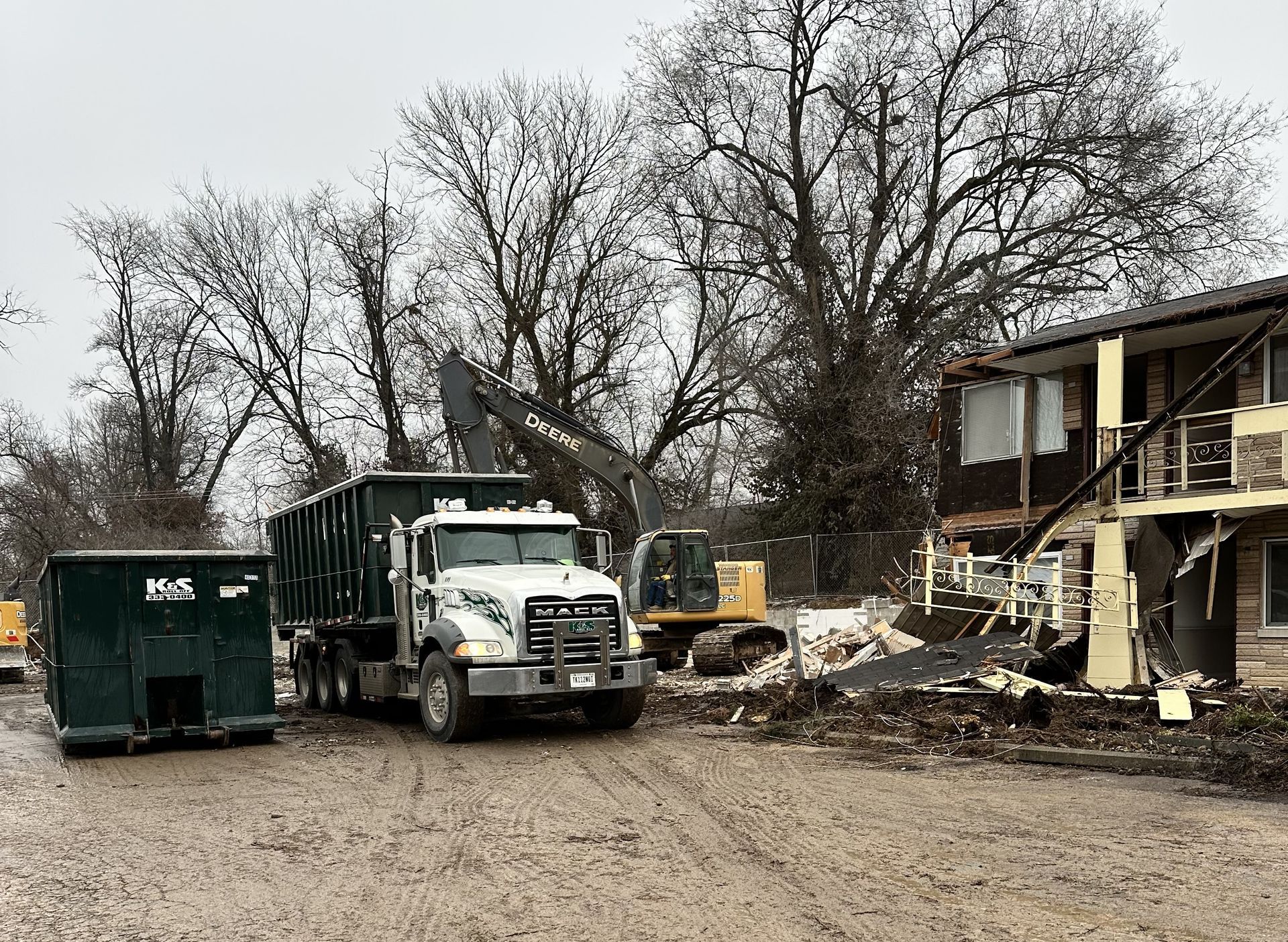 A dump truck is parked in front of a building being demolished.
