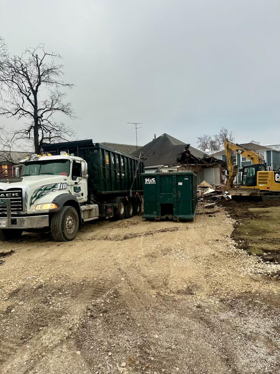 A dump truck is parked in a dirt lot next to a construction site.