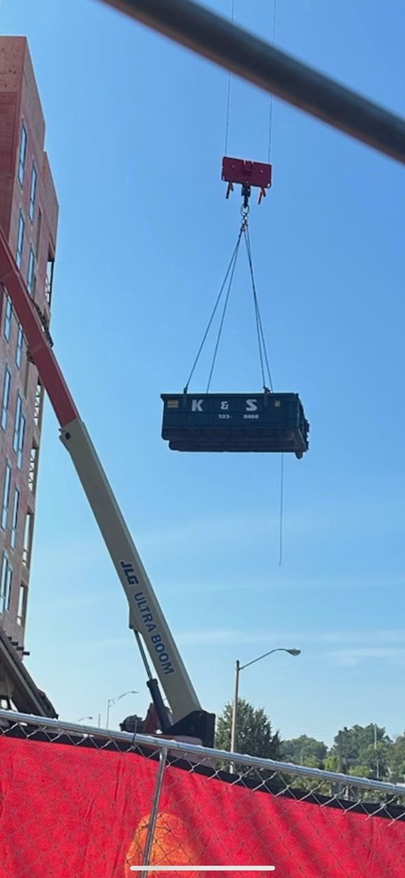 A large dumpster is being lifted into the air by a crane.