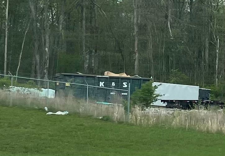 A large green dumpster is parked in front of a store called a center