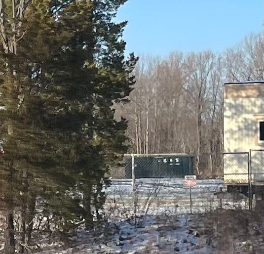 A large green dumpster is parked in front of a store called a center
