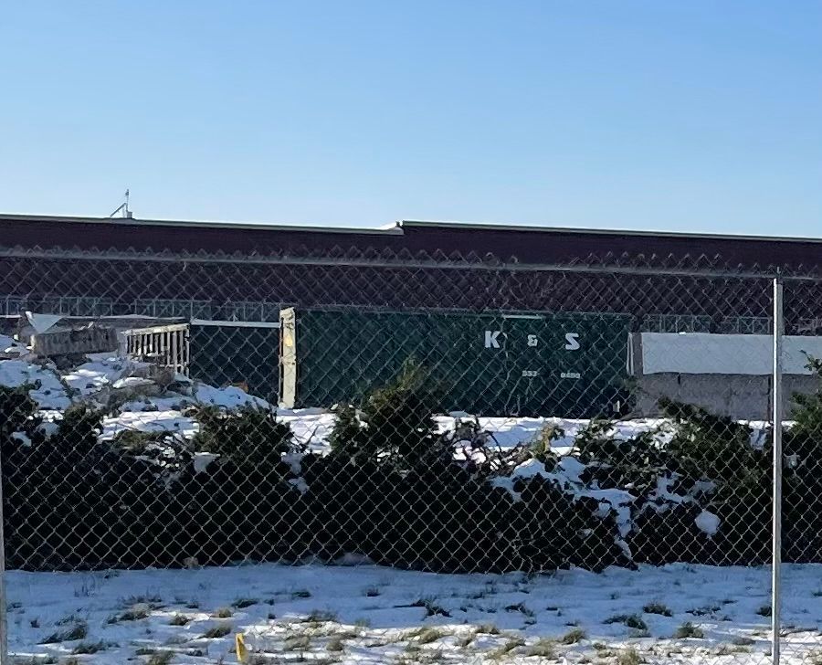 A large green dumpster is parked in front of a store called a center