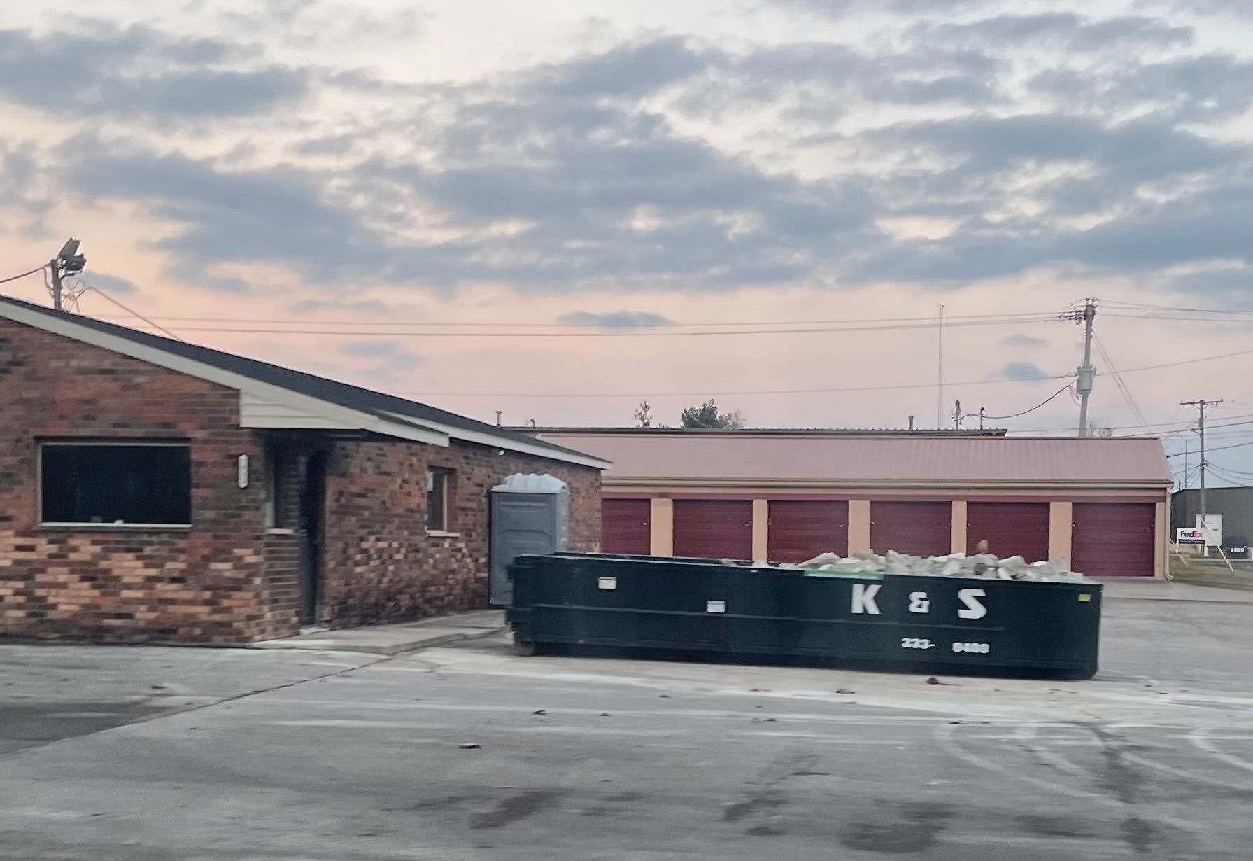 A large green dumpster is parked in front of a store called a center