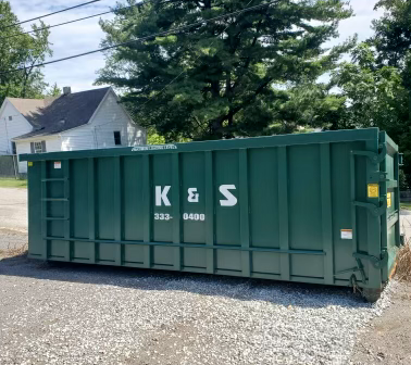 A green dumpster with the letters k & s on it