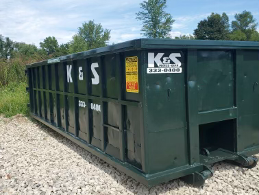 A green dumpster with the letters k & s on it