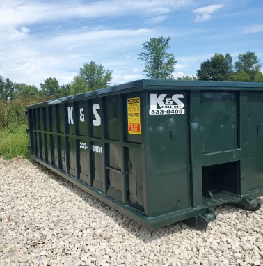 A green dumpster with the word ks on it