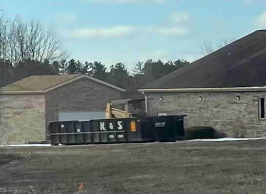 A large green dumpster is parked in front of a store called a center