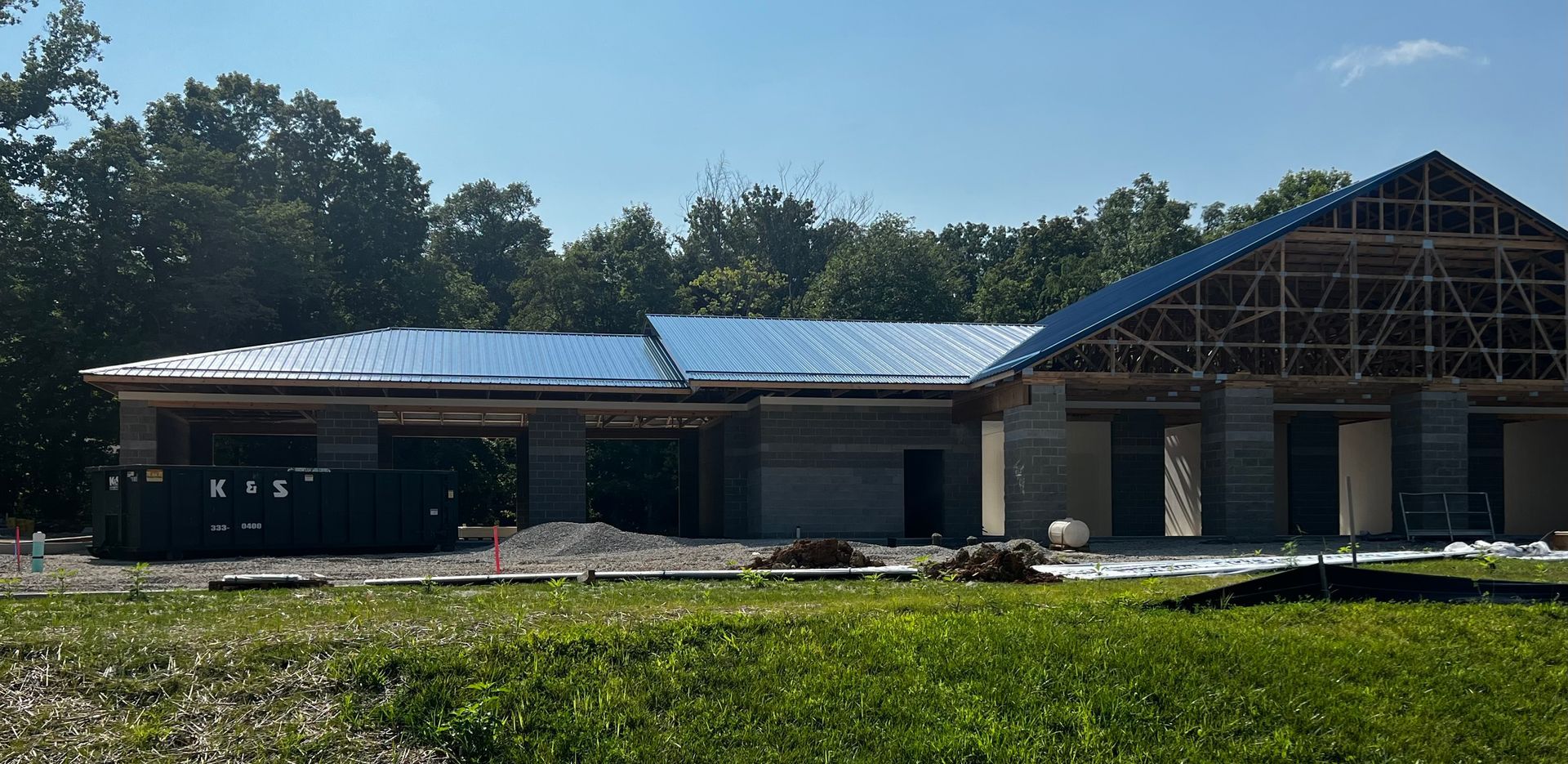 A large house is being built in the middle of a lush green field.