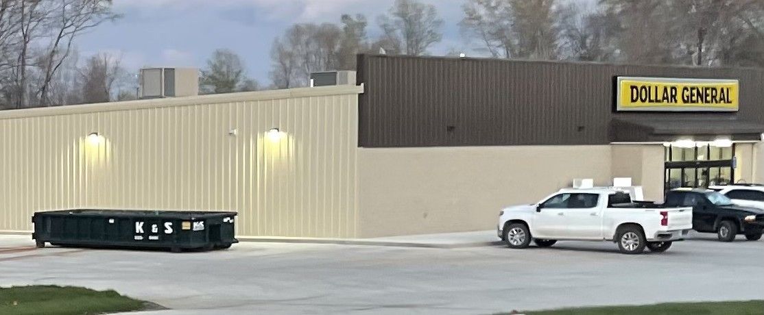 A white truck is parked in front of a dollar general store.
