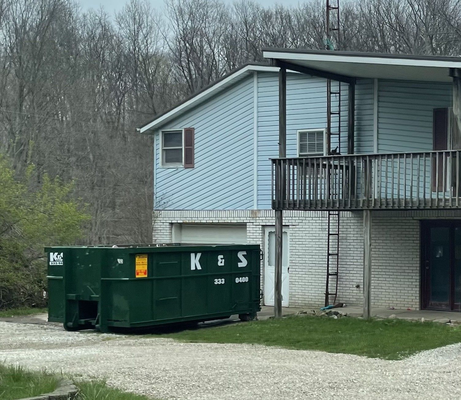A house with a green dumpster in front of it that says kes