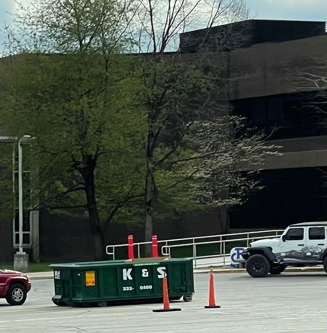 A green dumpster with ks written on it