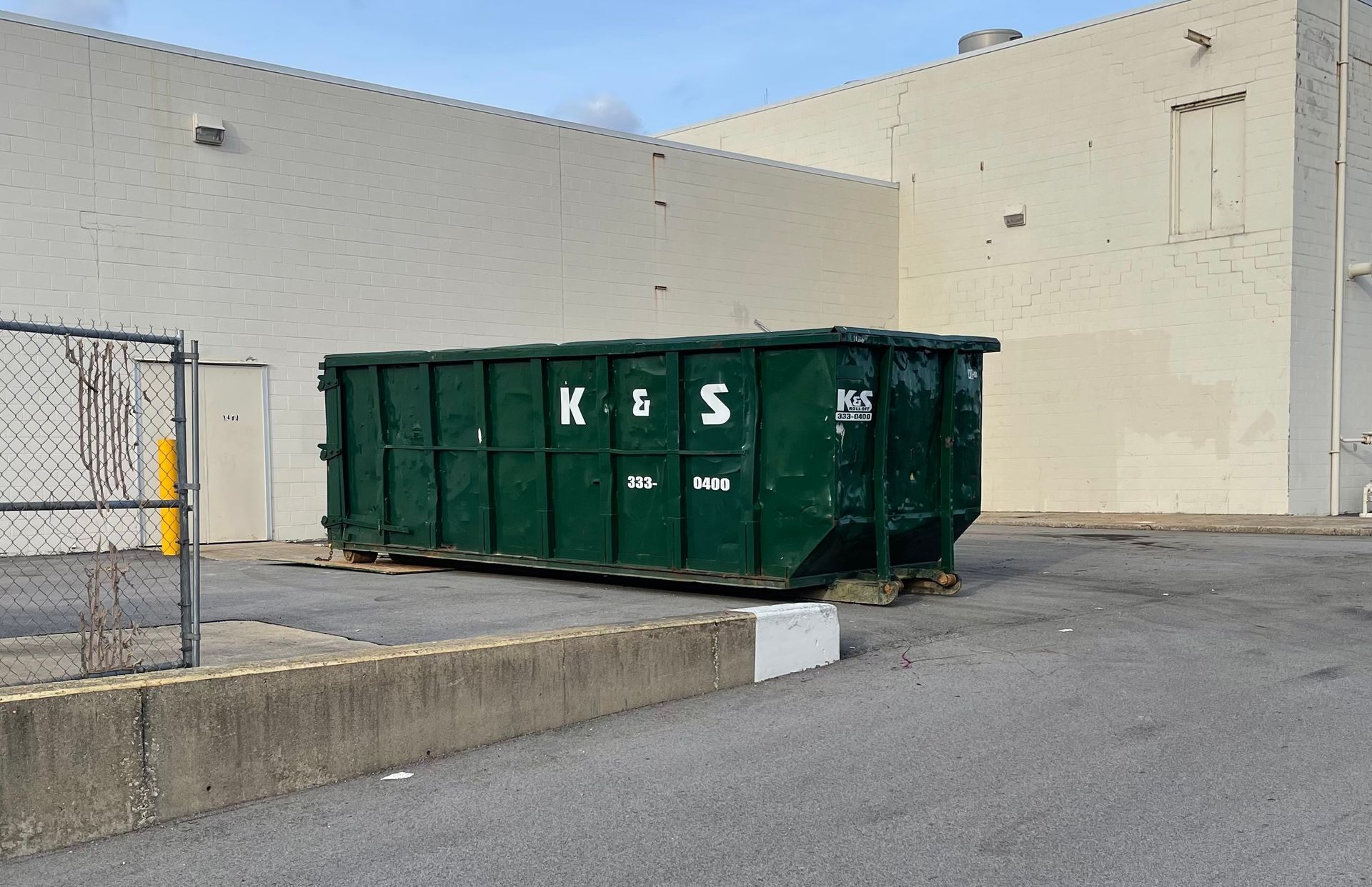 A large green dumpster is parked in front of a store called a center