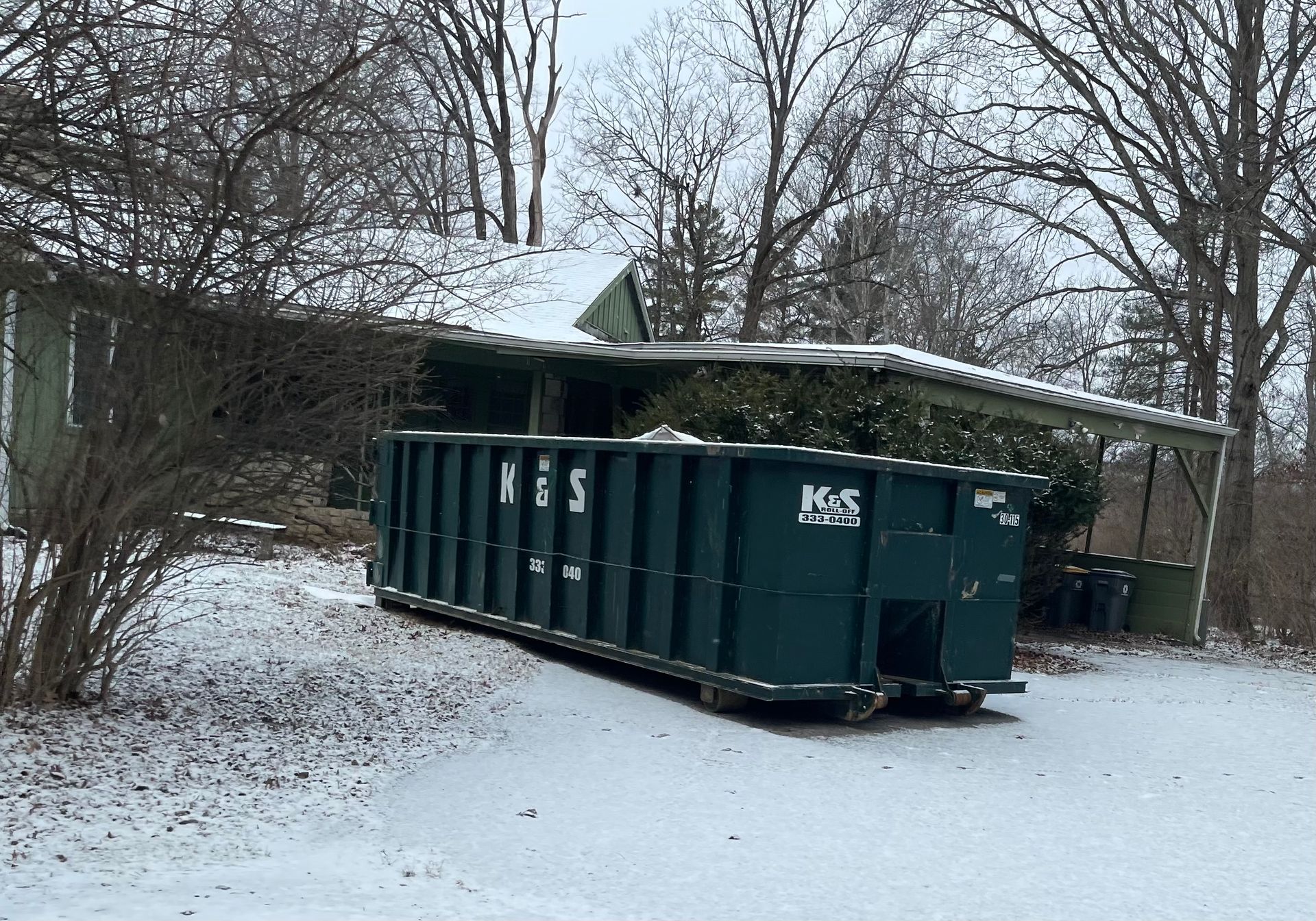 A large green dumpster is parked in front of a store called a center