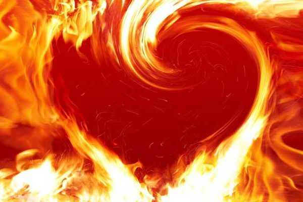 A close up of a heart made of flames on a white background.