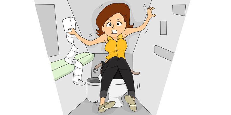 A woman is sitting on a toilet holding a roll of toilet paper.