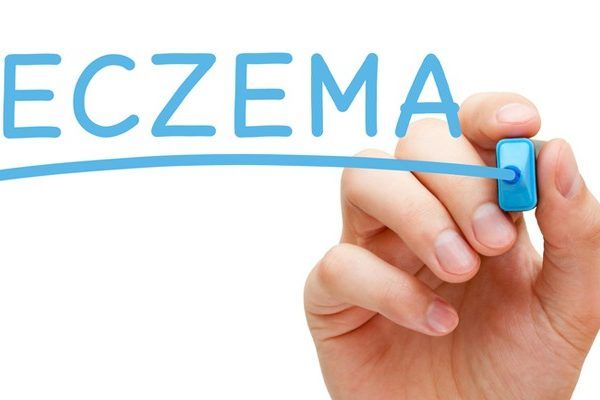 A person is writing the word eczema with a marker