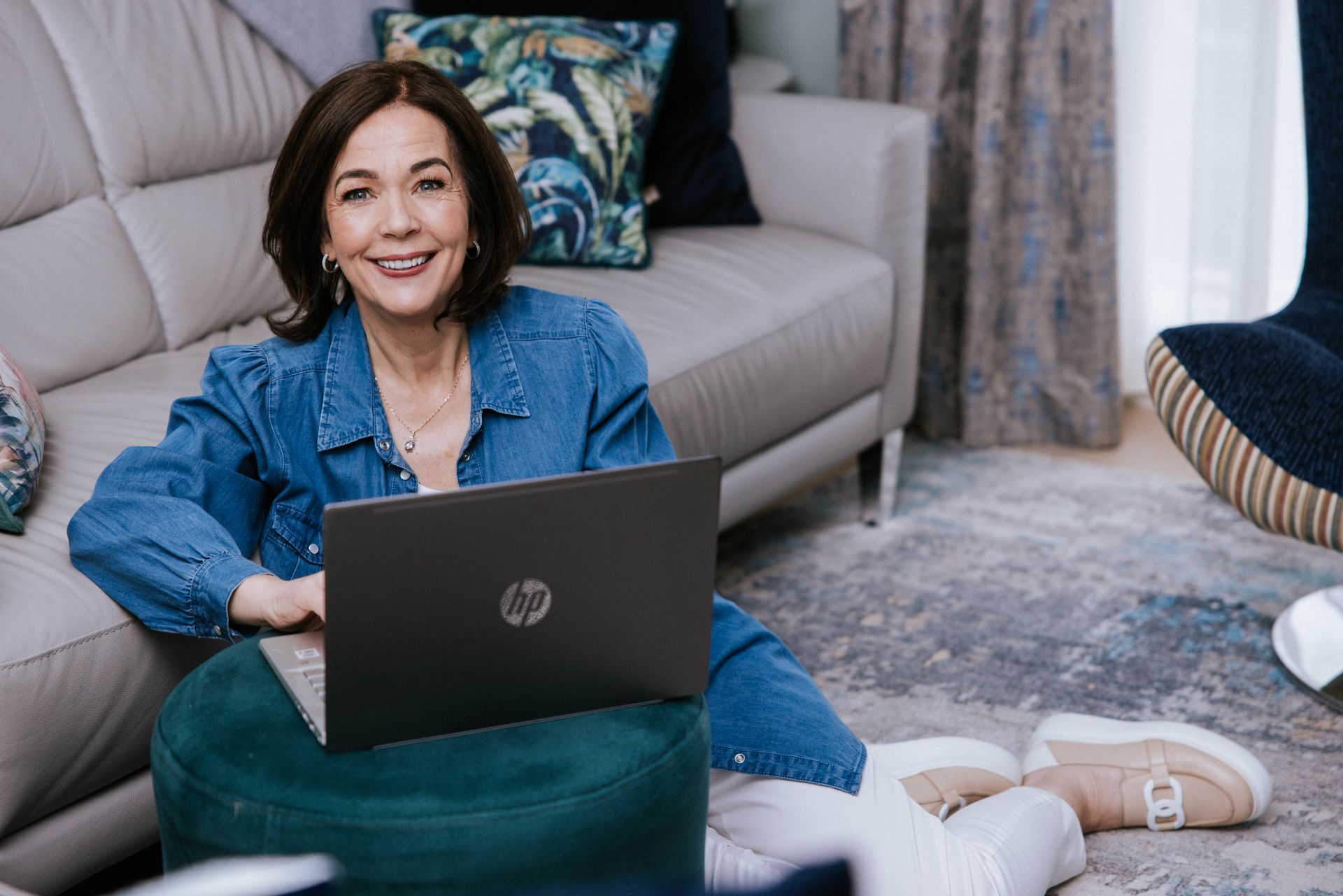 A woman is sitting on the floor using a laptop computer.