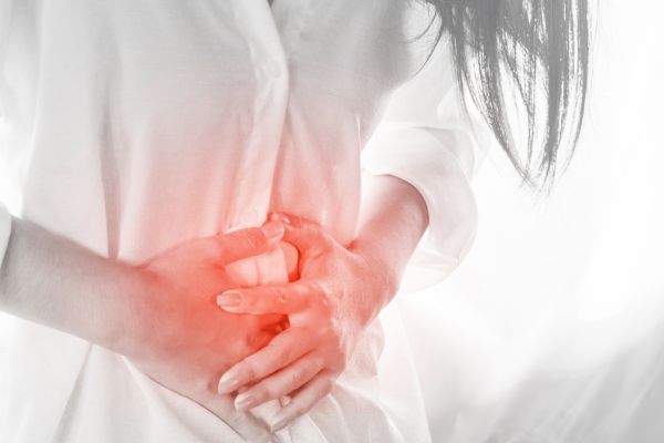 A woman is holding her stomach in pain.