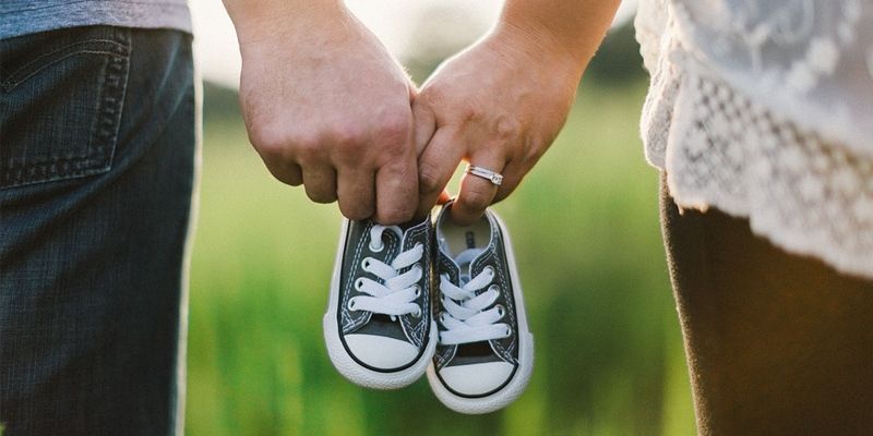 A man and a woman are holding a pair of baby shoes.