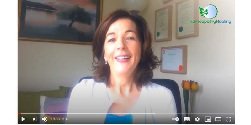 A woman is sitting in a chair and smiling in a video.