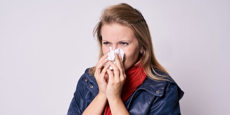 A woman is blowing her nose into a napkin.