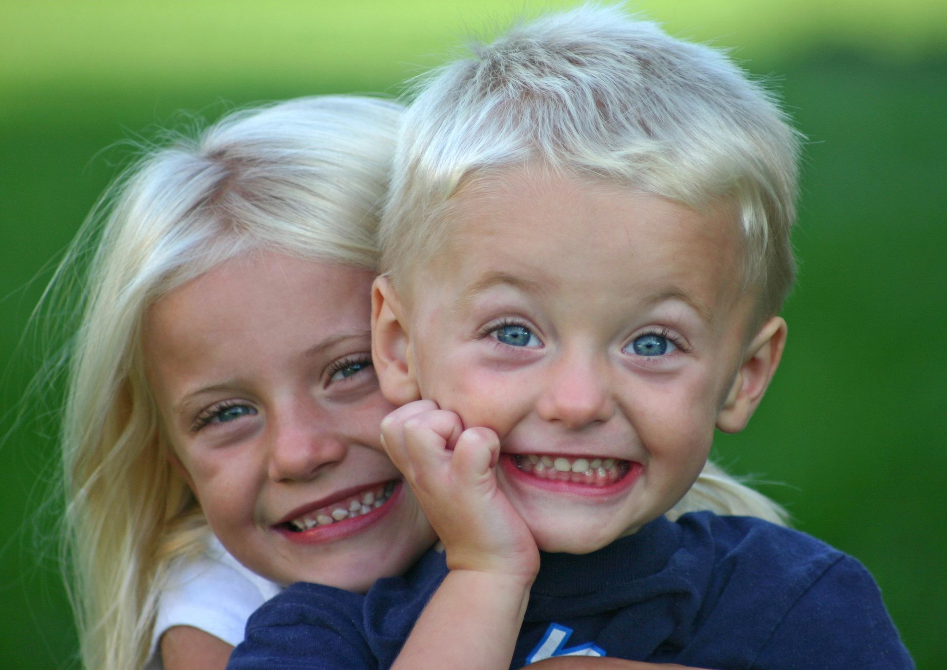 A boy and a girl are hugging each other and smiling for the camera.