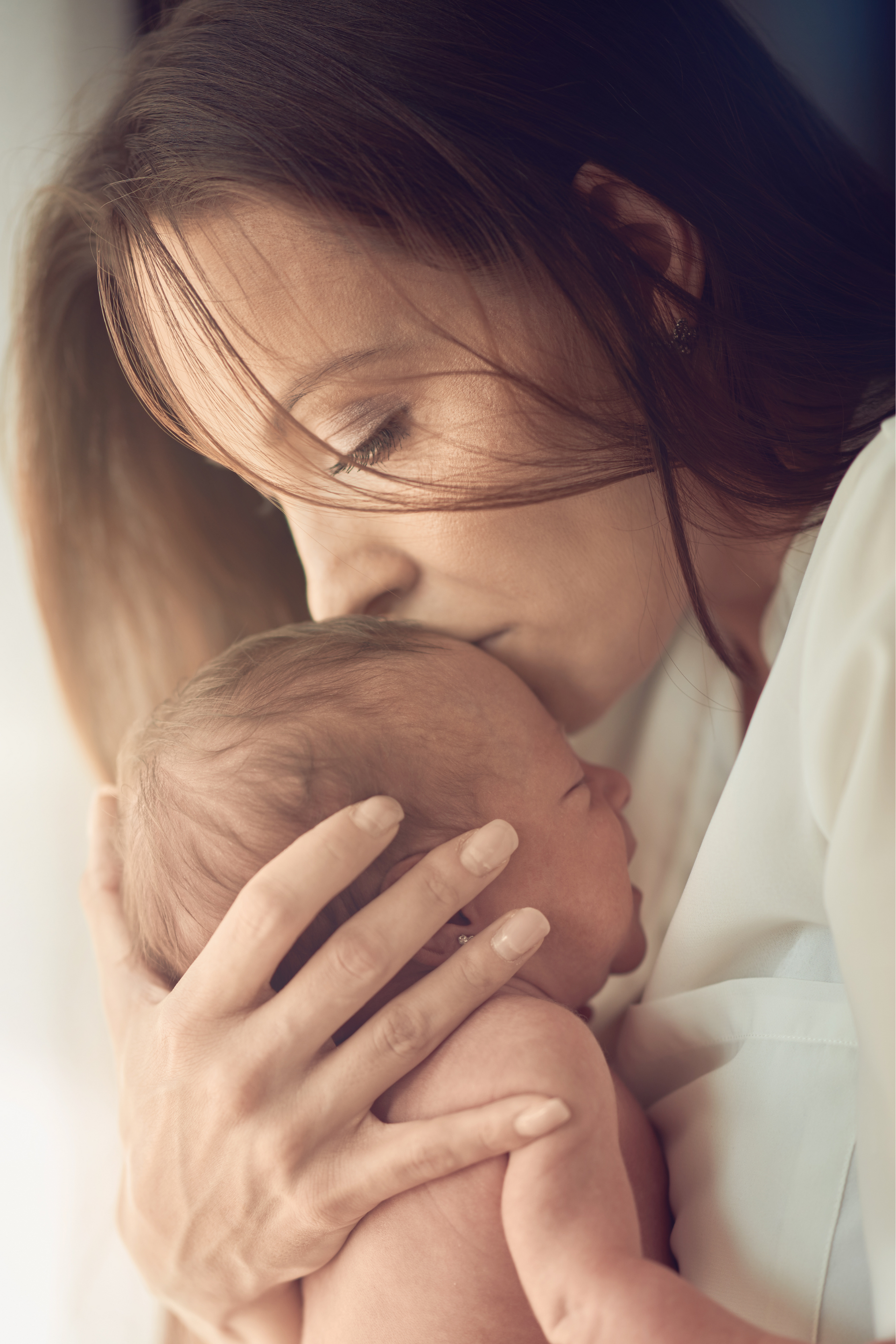 A woman is holding a baby in her arms and kissing it on the cheek.