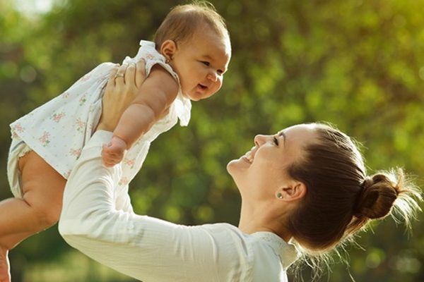 A woman is holding a baby in her arms in the air.