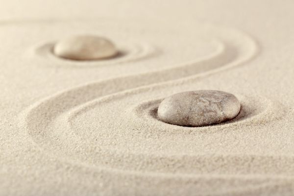 Two rocks are sitting in the sand in a zen garden.