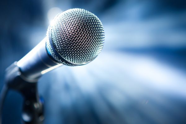 A close up of a microphone on a stand in front of a blue background.