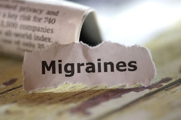 A piece of torn paper with the word migraines on it