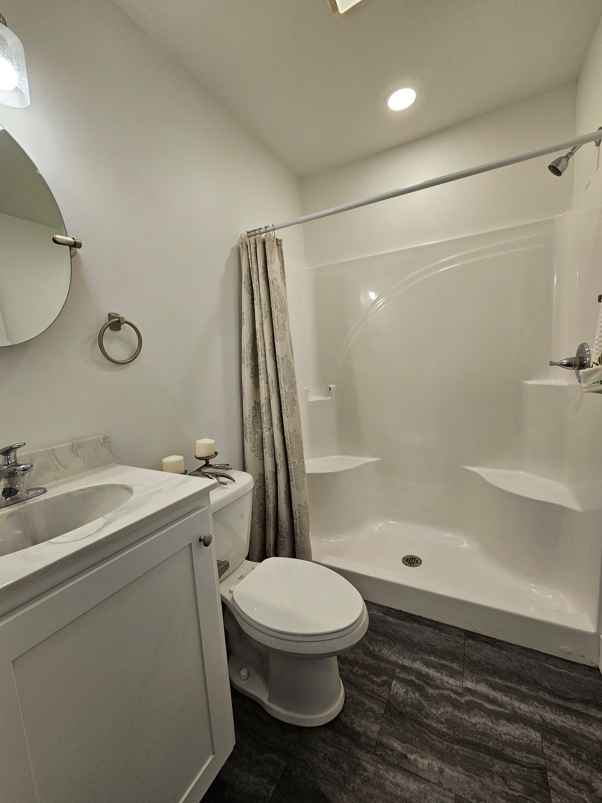 A bathroom with a toilet , sink , shower and mirror.