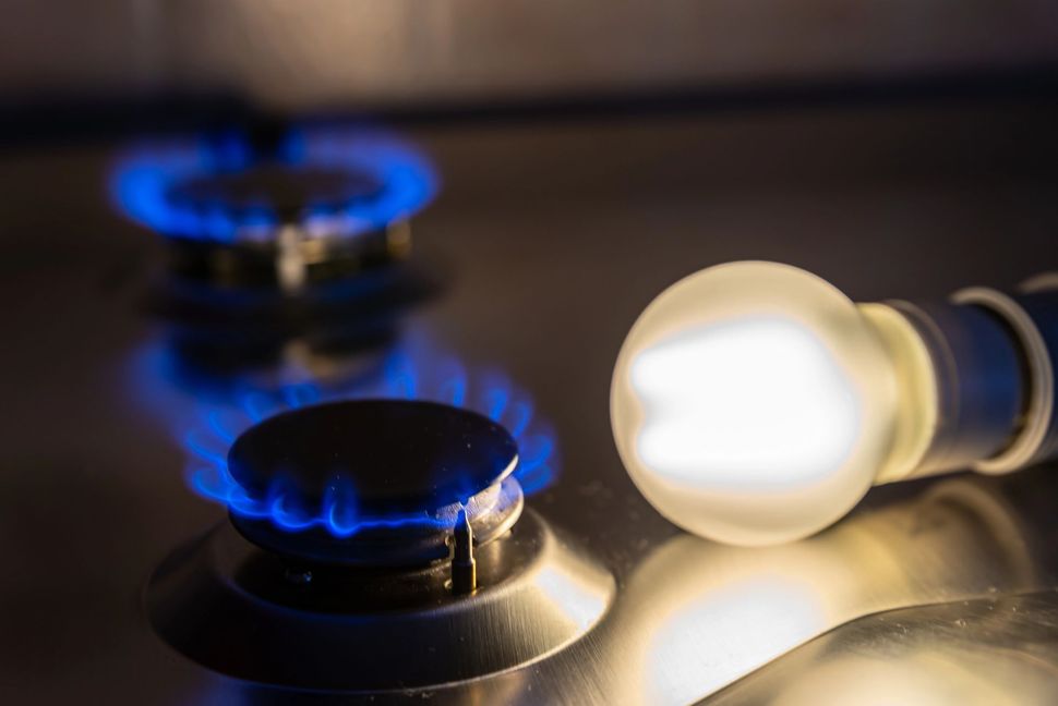 Fiamme blu dei fornelli accanto a una lampadina accesa su una superficie metallica