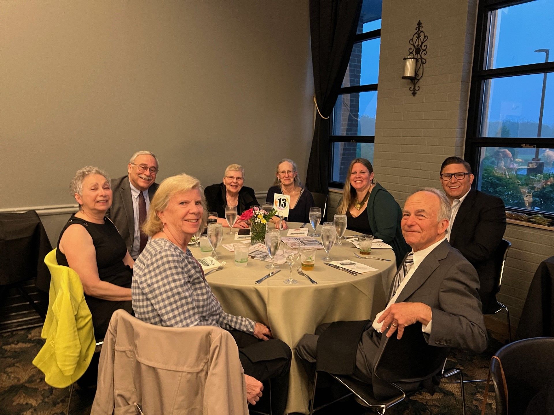 Group of people seated around a round table in a well-lit room, possibly at a formal event.
