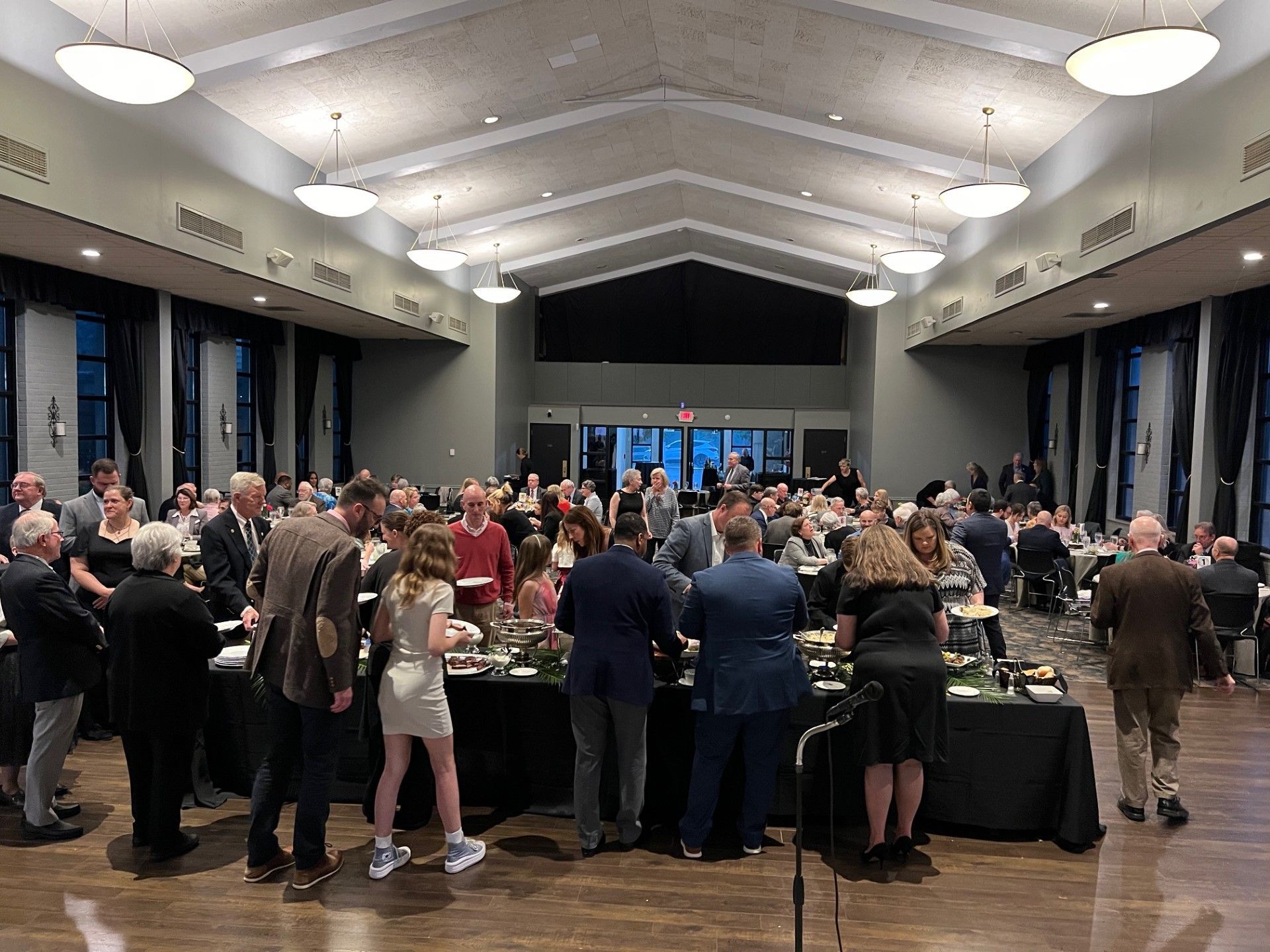 Large event in a hall; many people gathered around tables, likely for a meal.