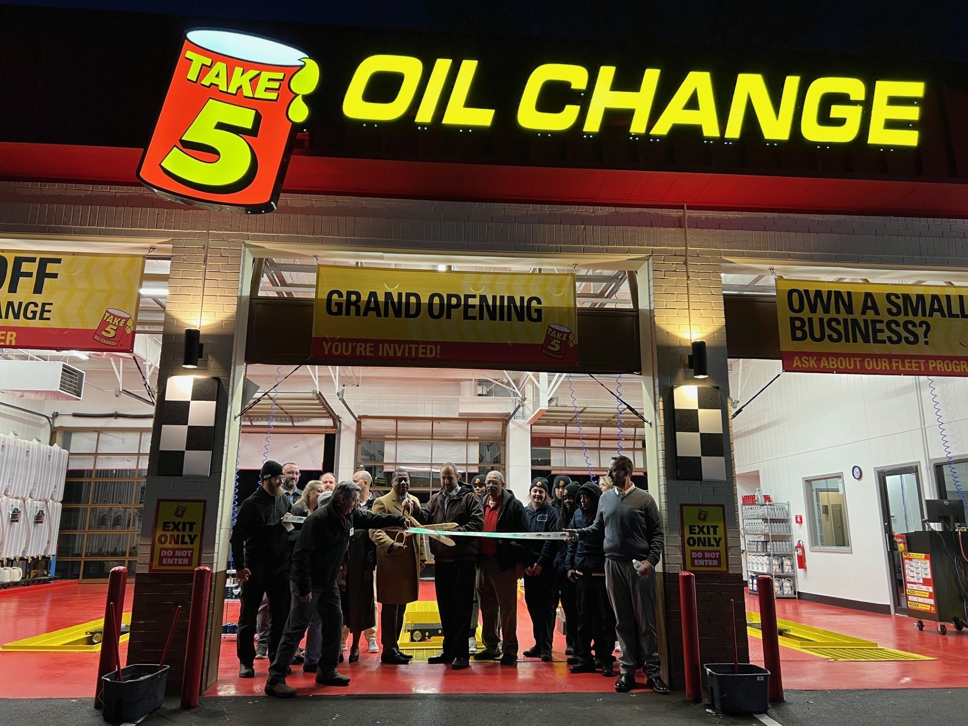People cutting a ribbon at the grand opening of a Take 5 Oil Change shop.