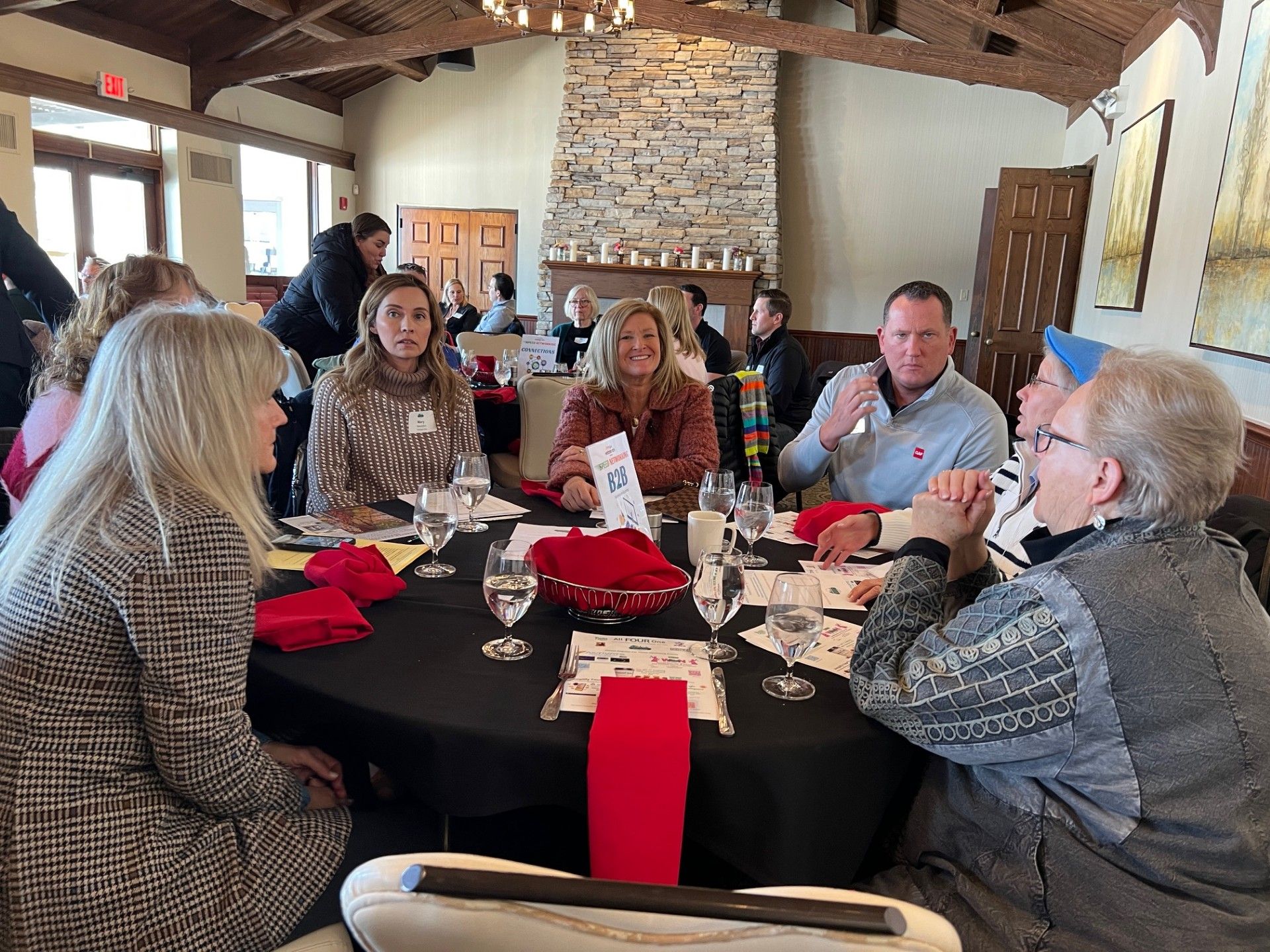 People seated around a black table with red accents in a restaurant. They are talking and drinking water.