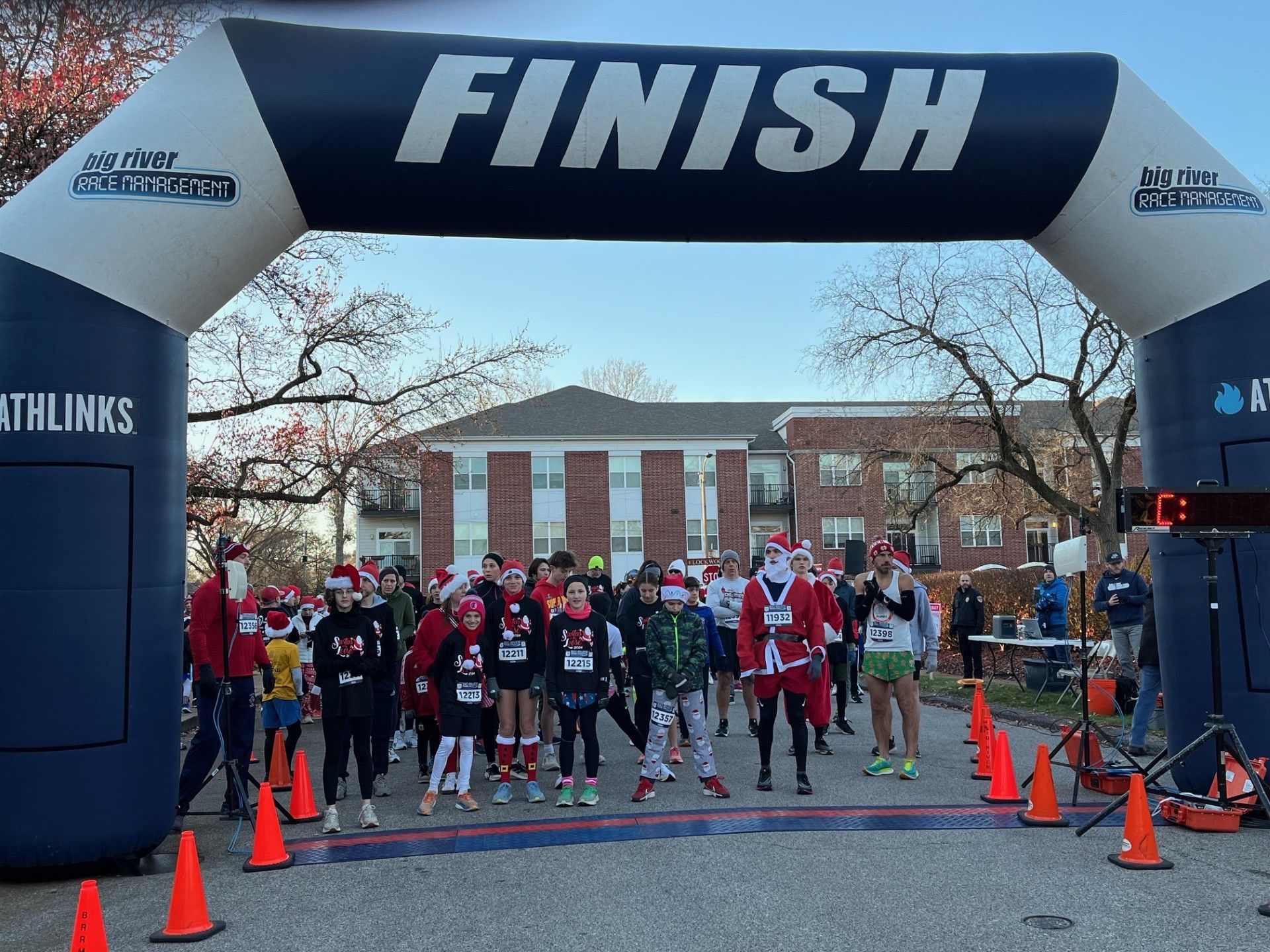 Runners in Santa hats line up at a race start under a 