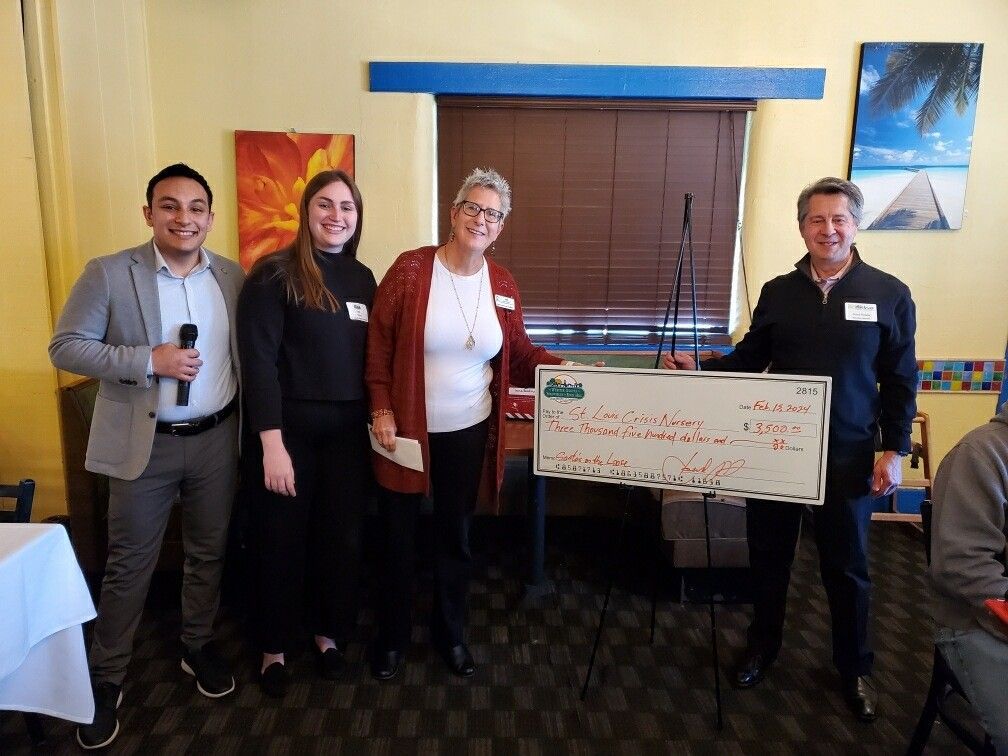 Four people holding a large check in a restaurant. They are smiling.