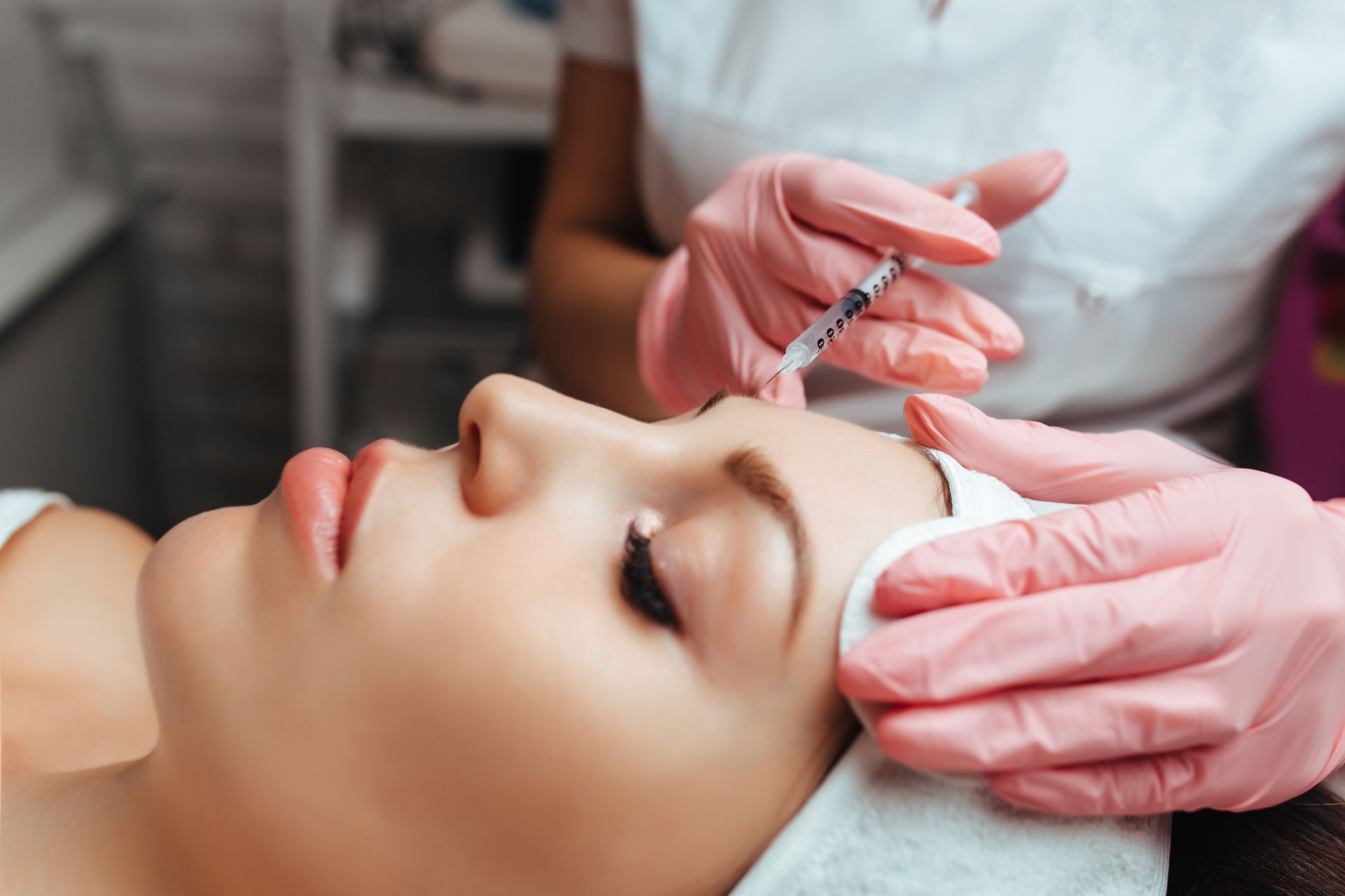 A clinician in gloves preparing to administer a Botox injection.