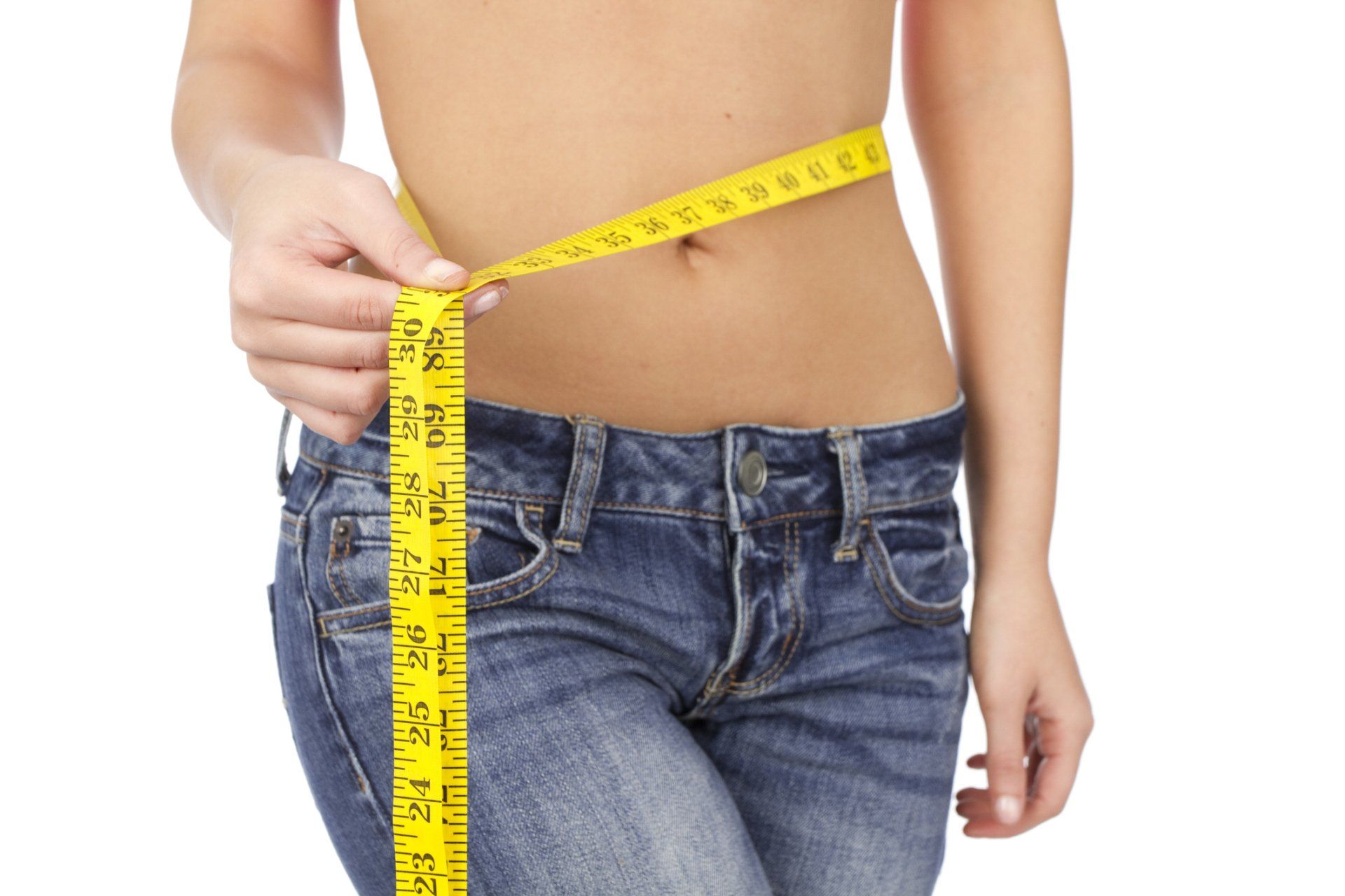 Person measuring their waist with a yellow tape measure, wearing blue jeans.