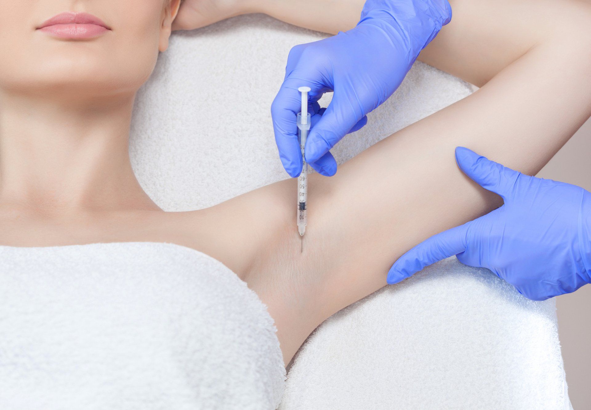 Person receiving an underarm injection, in a medical setting.