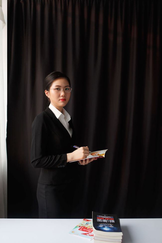 Professional woman in a navy blazer standing in a modern office, facing the camera with a slight smile