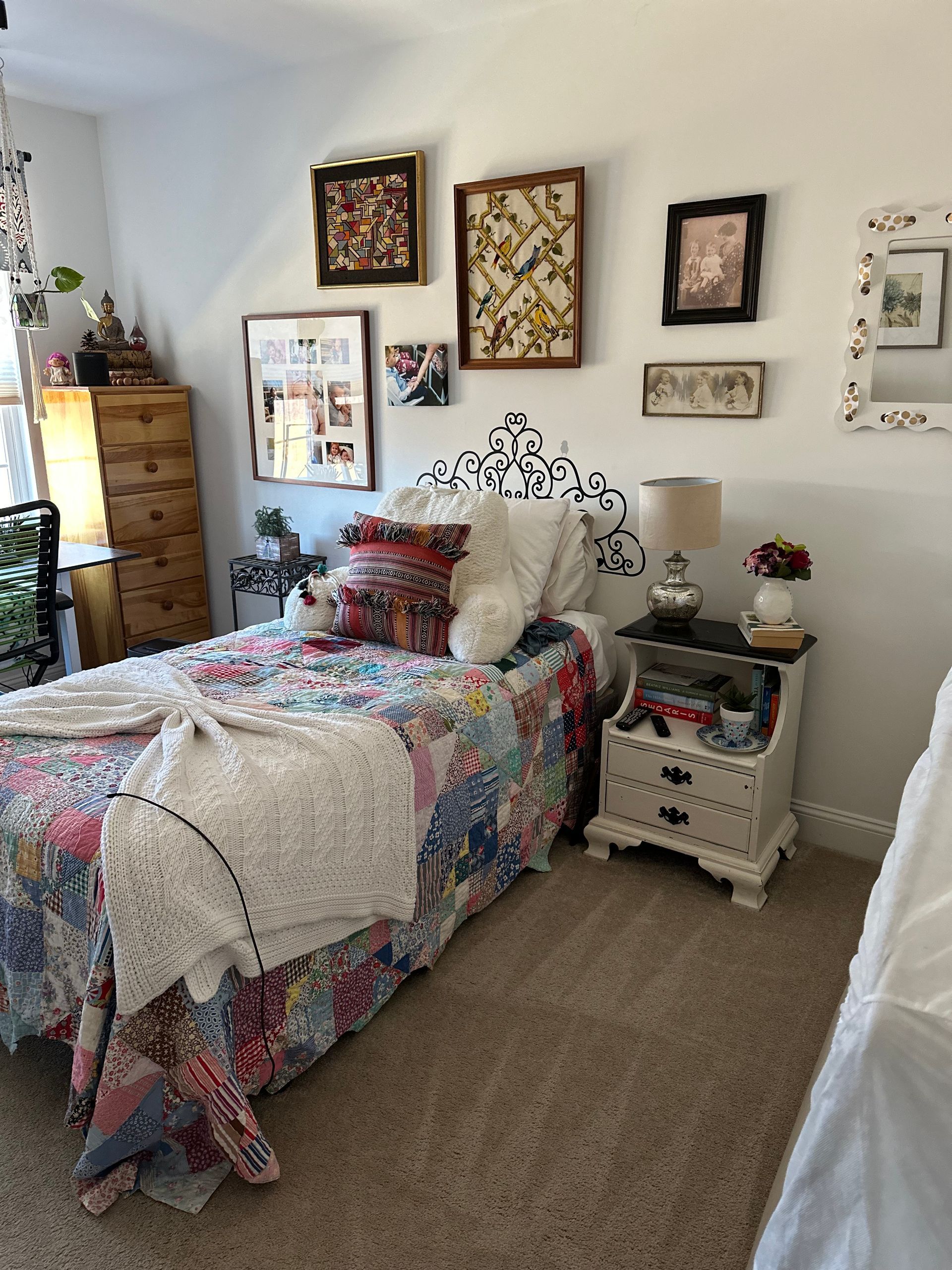 A bedroom featuring a bed with a colorful patchwork quilt, a decorative headboard decal, and a gallery wall of framed art.