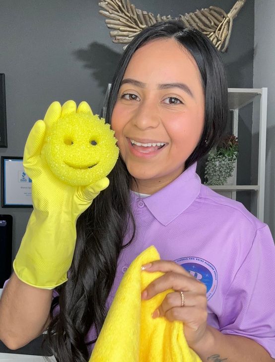 holds a yellow smiley-face sponge and a yellow microfiber cloth. cleaning with Blanca Sparkle & Shine 